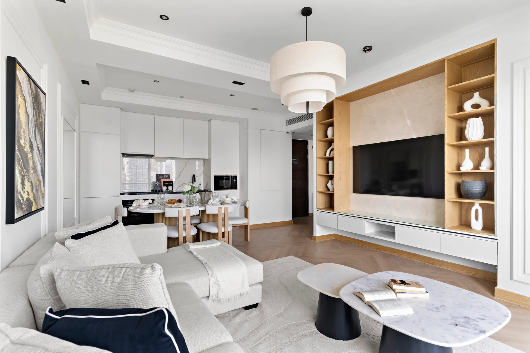 A bright living room with a television wall and an open kitchen behind the seating area.