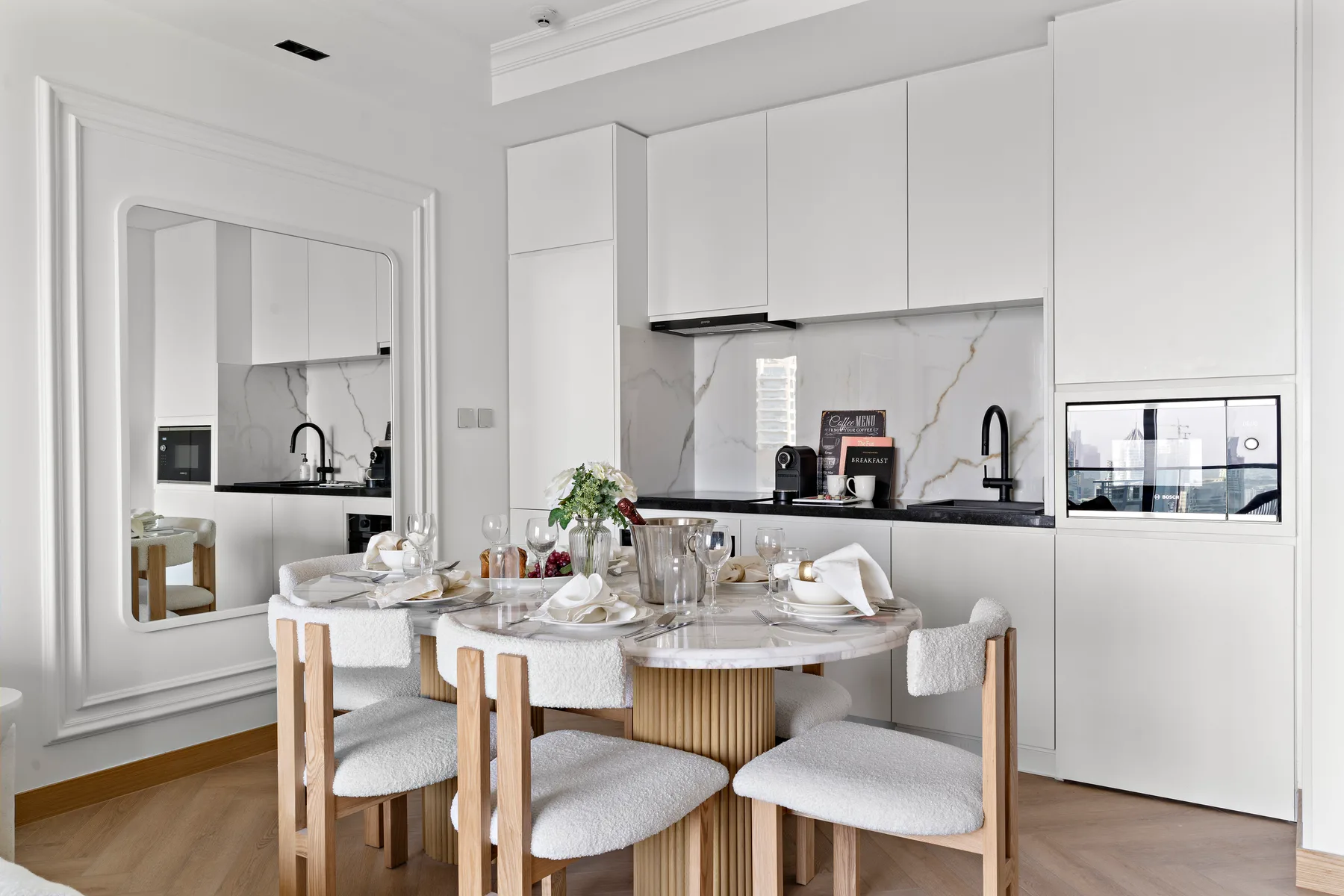 Un comedor luminoso con la mesa puesta junto a una cocina moderna.