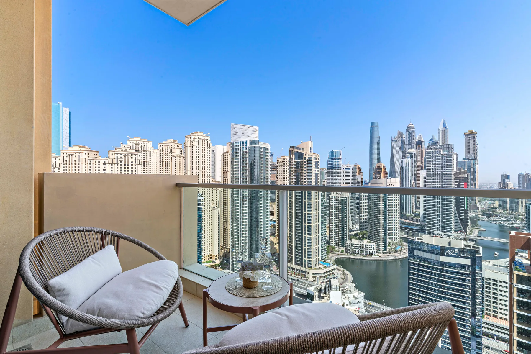 A balcony seating area overlooks a cluster of high-rise buildings.