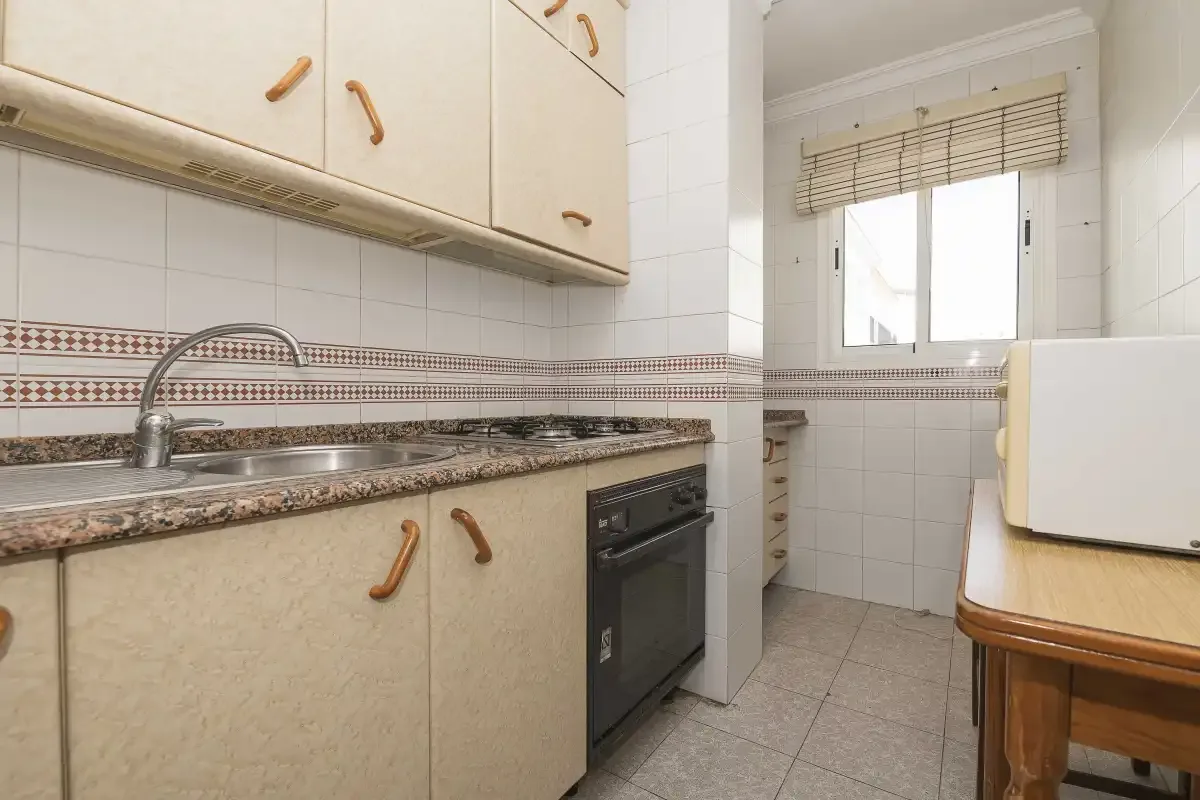 A kitchen with a sink, oven, and window.