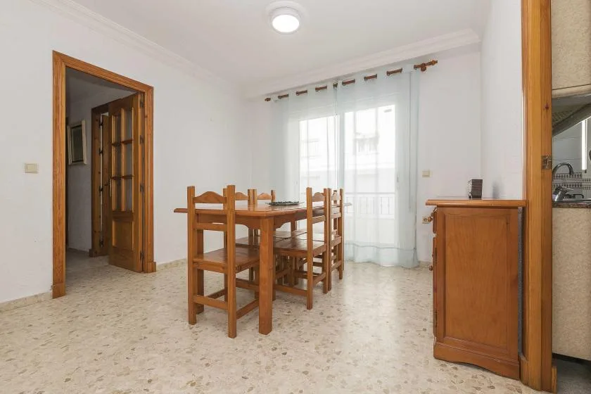 A dining area with a wooden table and chairs beside a bright window.