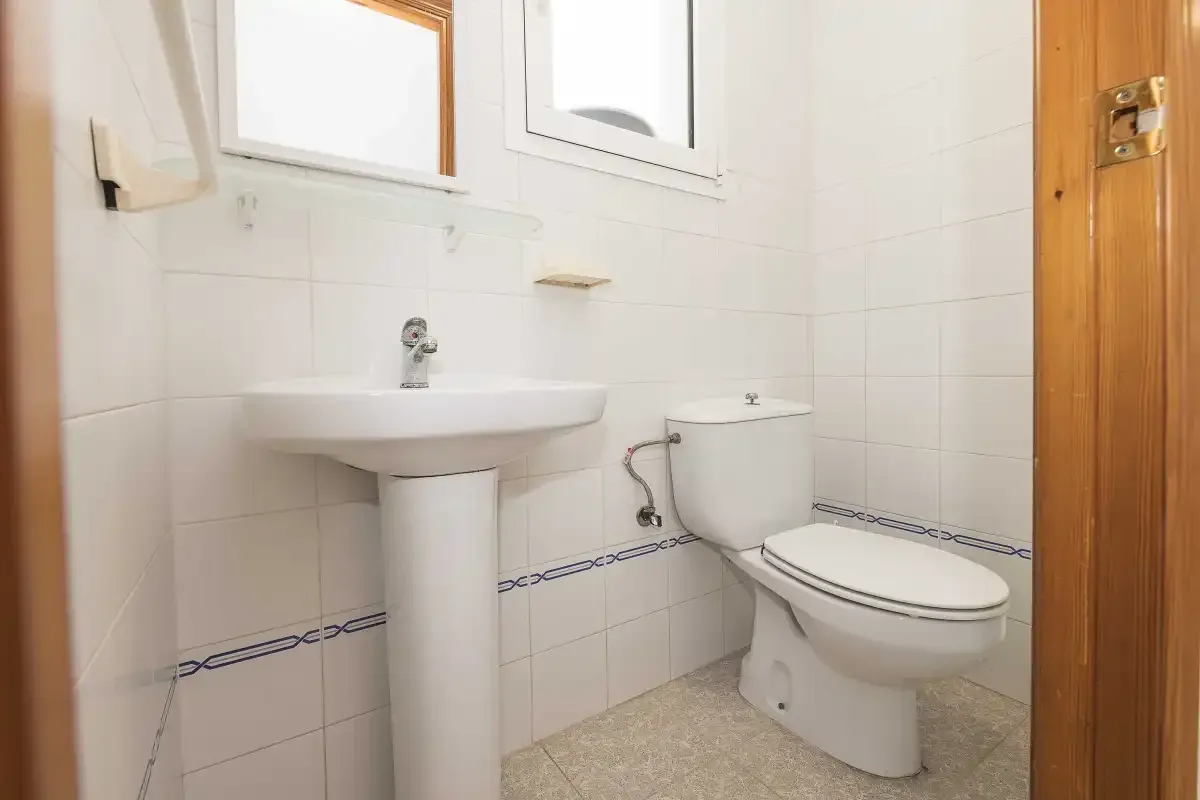 A tiled bathroom with a pedestal sink and toilet.