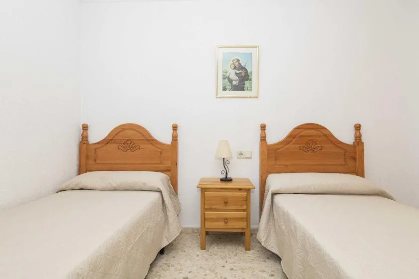 A twin bedroom with two beds and a small nightstand between them.
