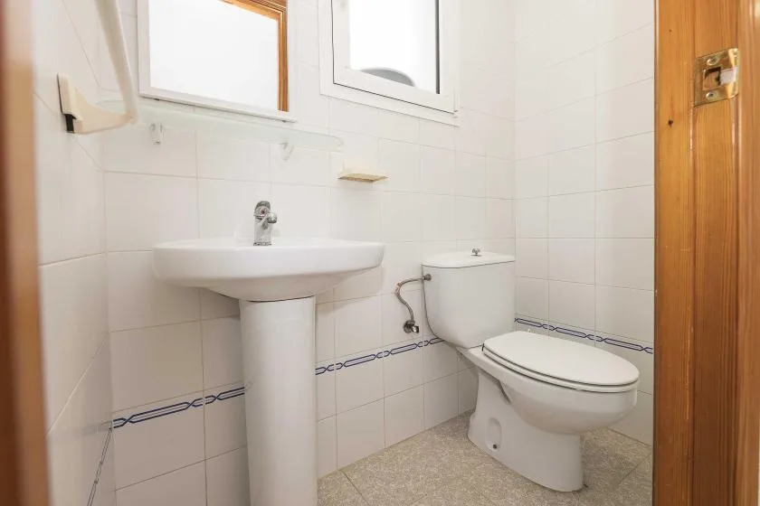 A tiled bathroom with a pedestal sink and toilet.