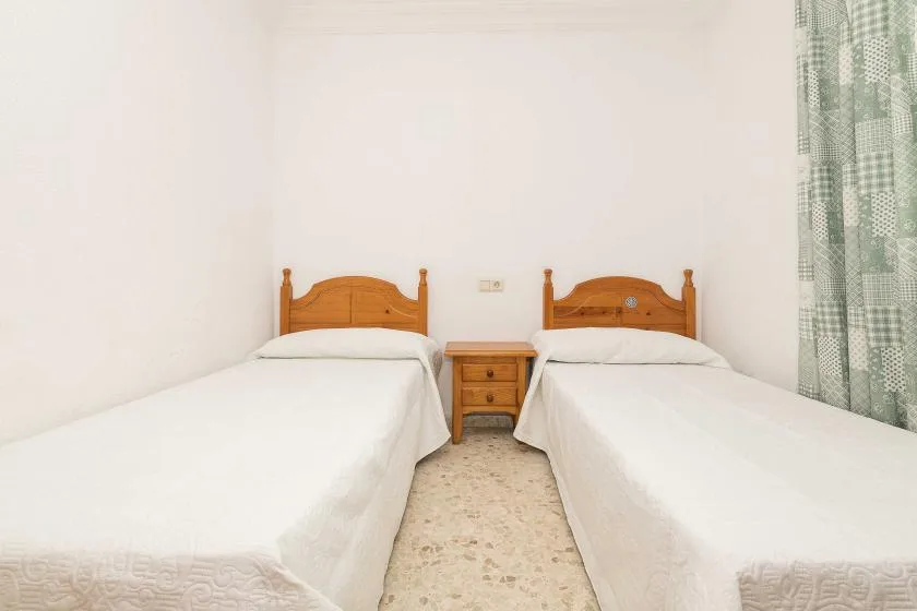 A bedroom with two single beds and a small bedside table.
