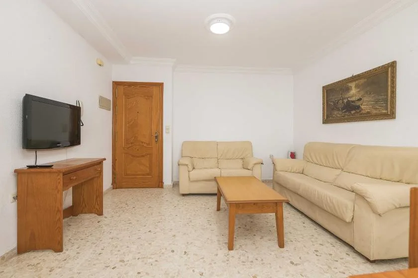 A living room with beige seating, a wooden coffee table, and a television.