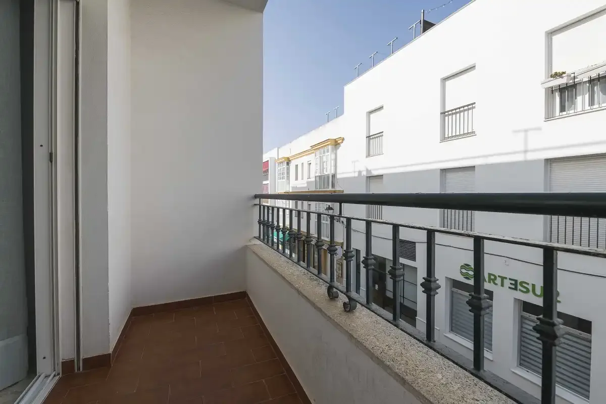 A small balcony with dark railing overlooks a row of buildings.