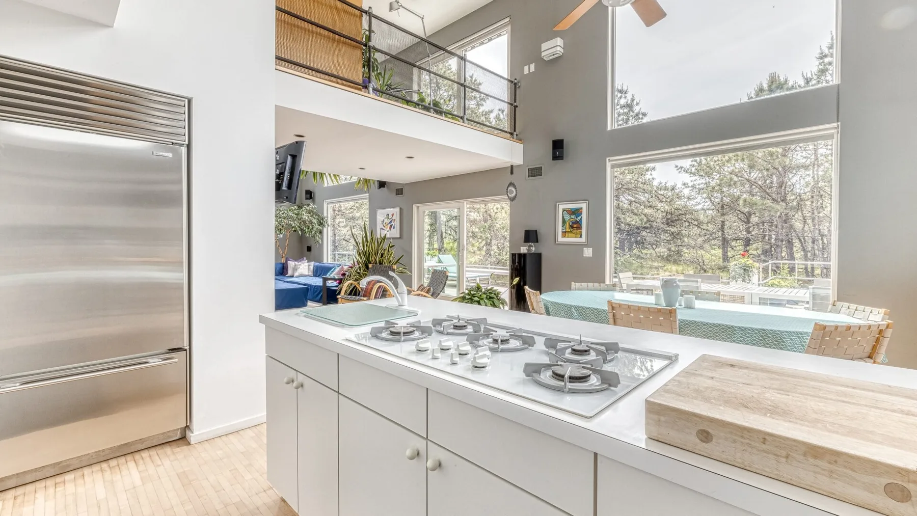 A bright open kitchen with a white island and large windows.