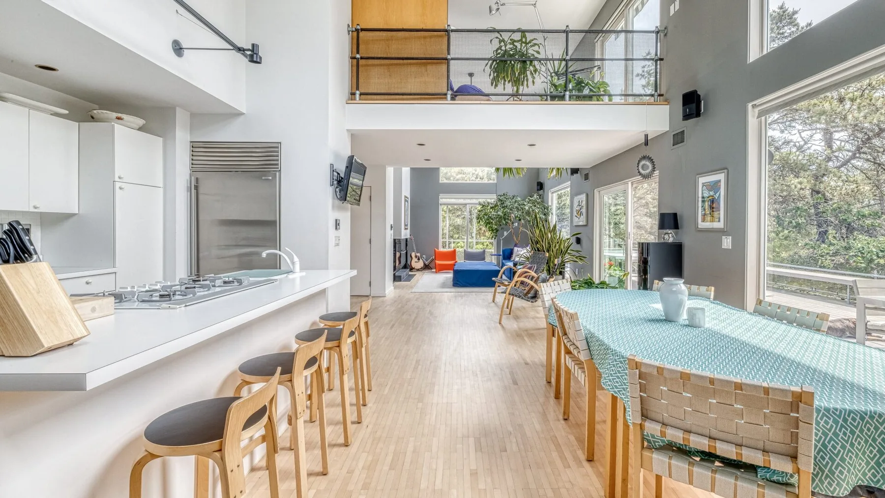 A bright open-plan kitchen and dining area with a long table and bar seating.