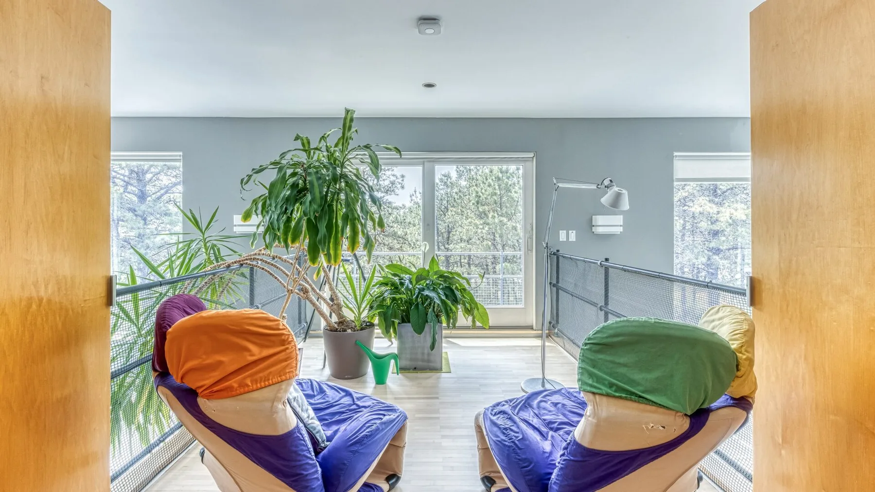 A bright room with two reclining seats, large windows, and several plants.