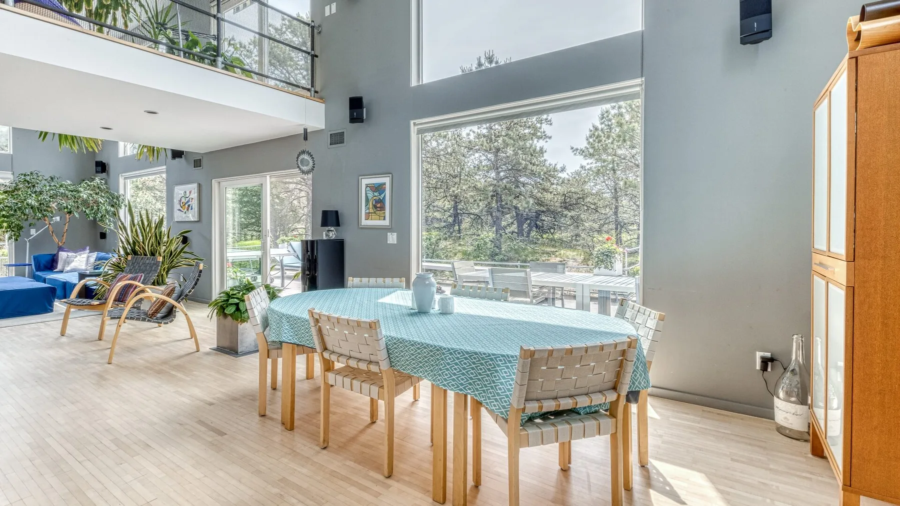 A dining area with a long table set beside large windows.