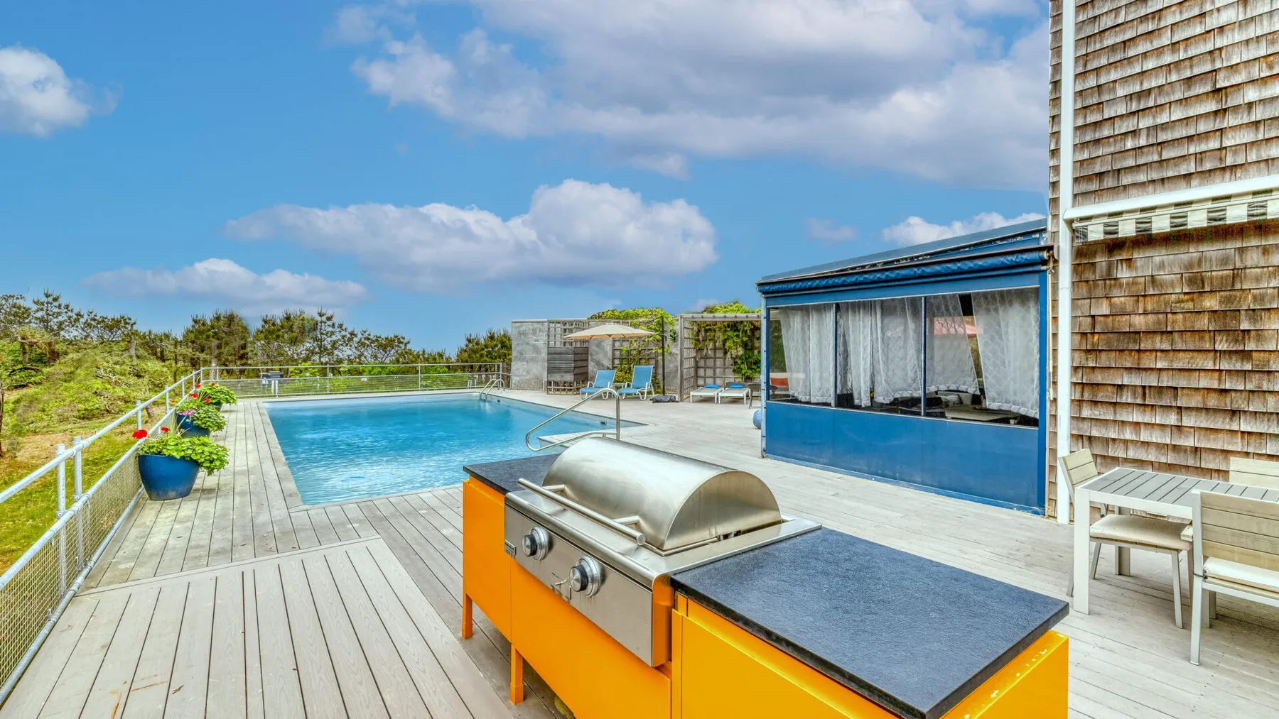 An outdoor pool deck with a built-in grill beside the water.