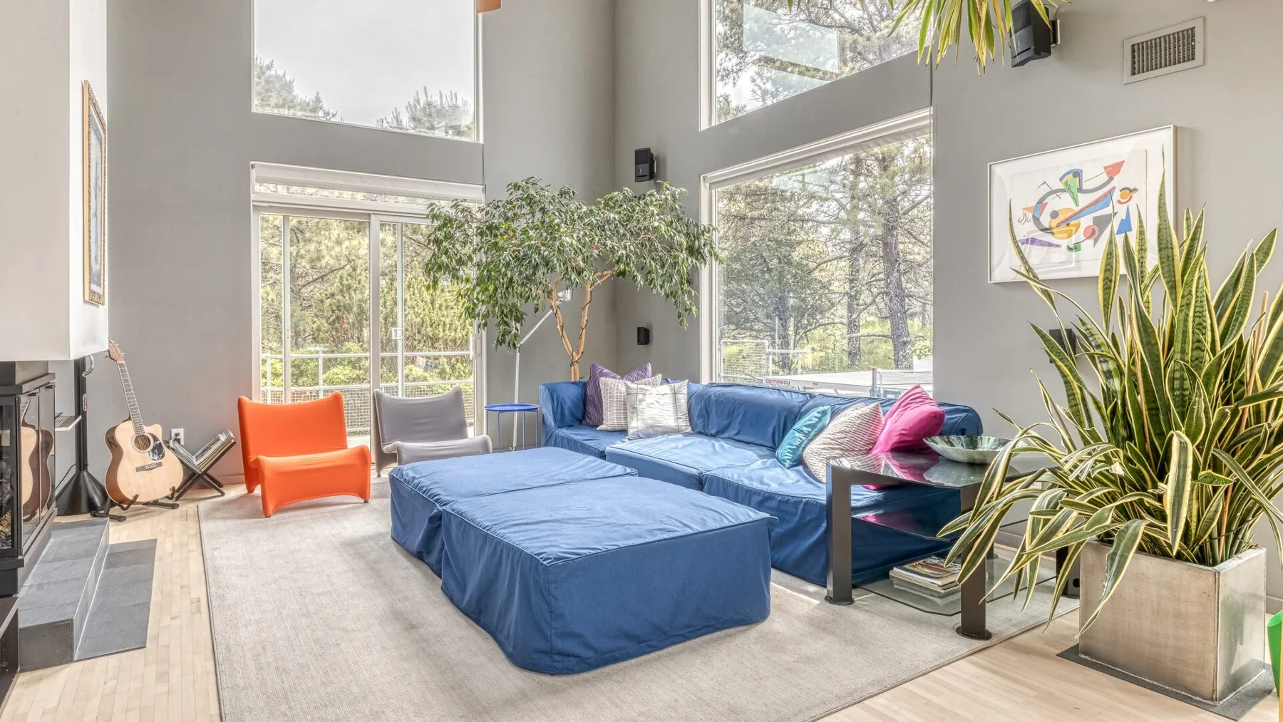 A bright living room with blue seating, a low table, and large windows.