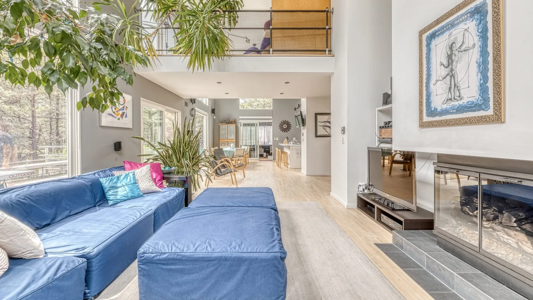 A bright living room with blue seating and large windows.