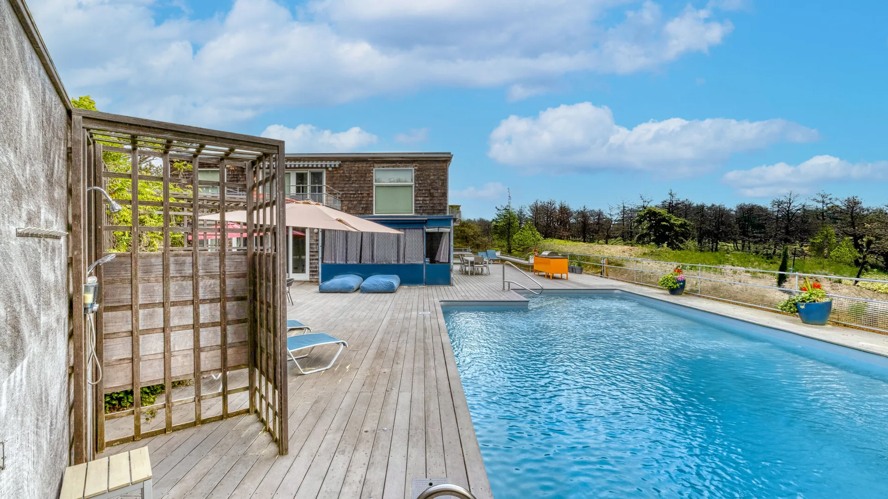 An outdoor swimming pool beside a wooden deck and modern building.