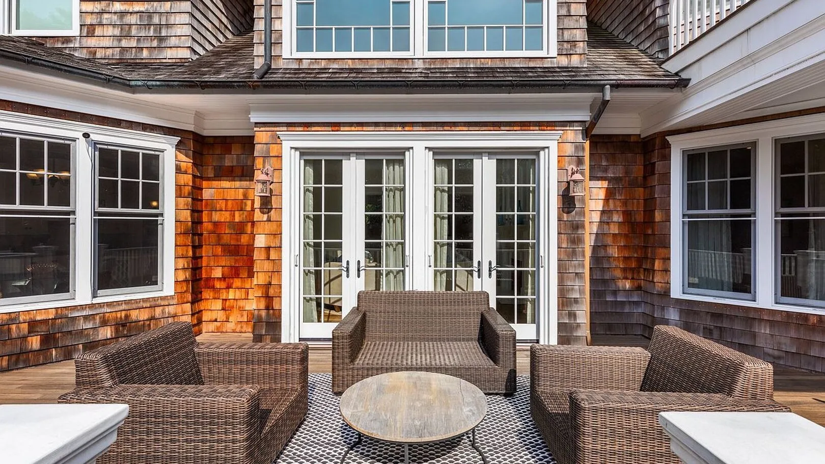 An outdoor patio with woven seating and glass doors.