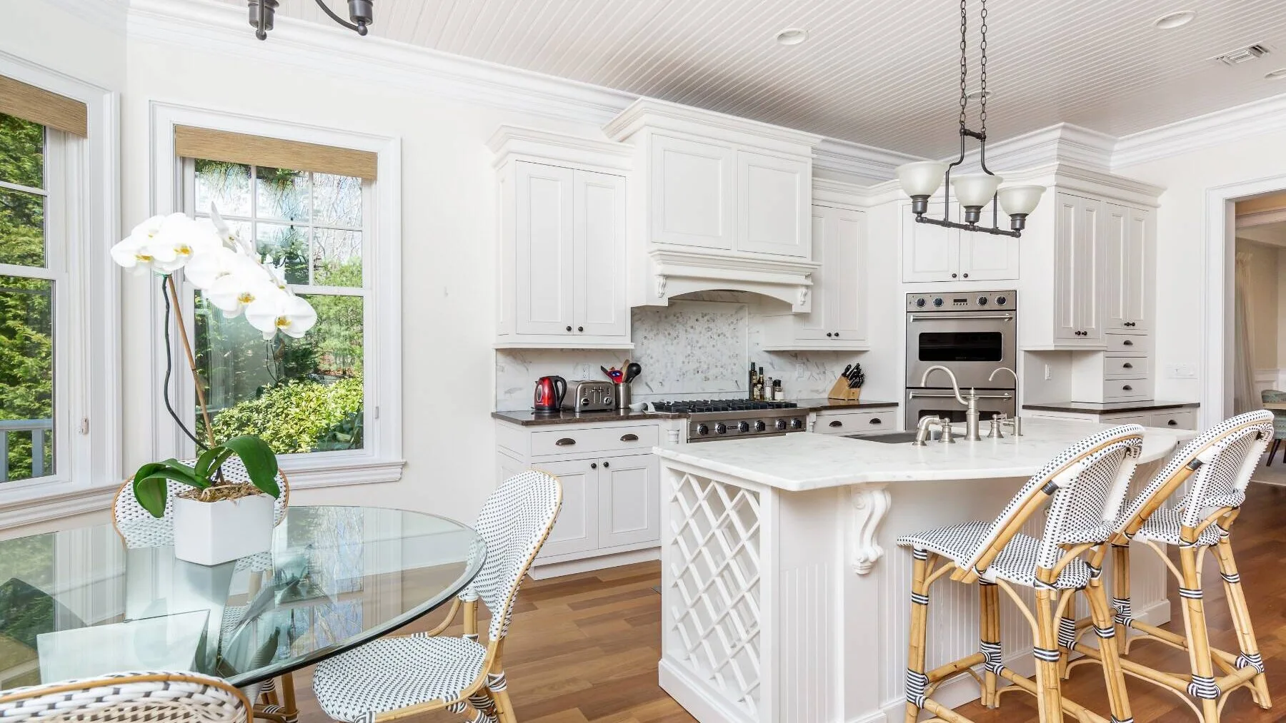 A bright kitchen with white cabinetry, a central island, and counter seating.