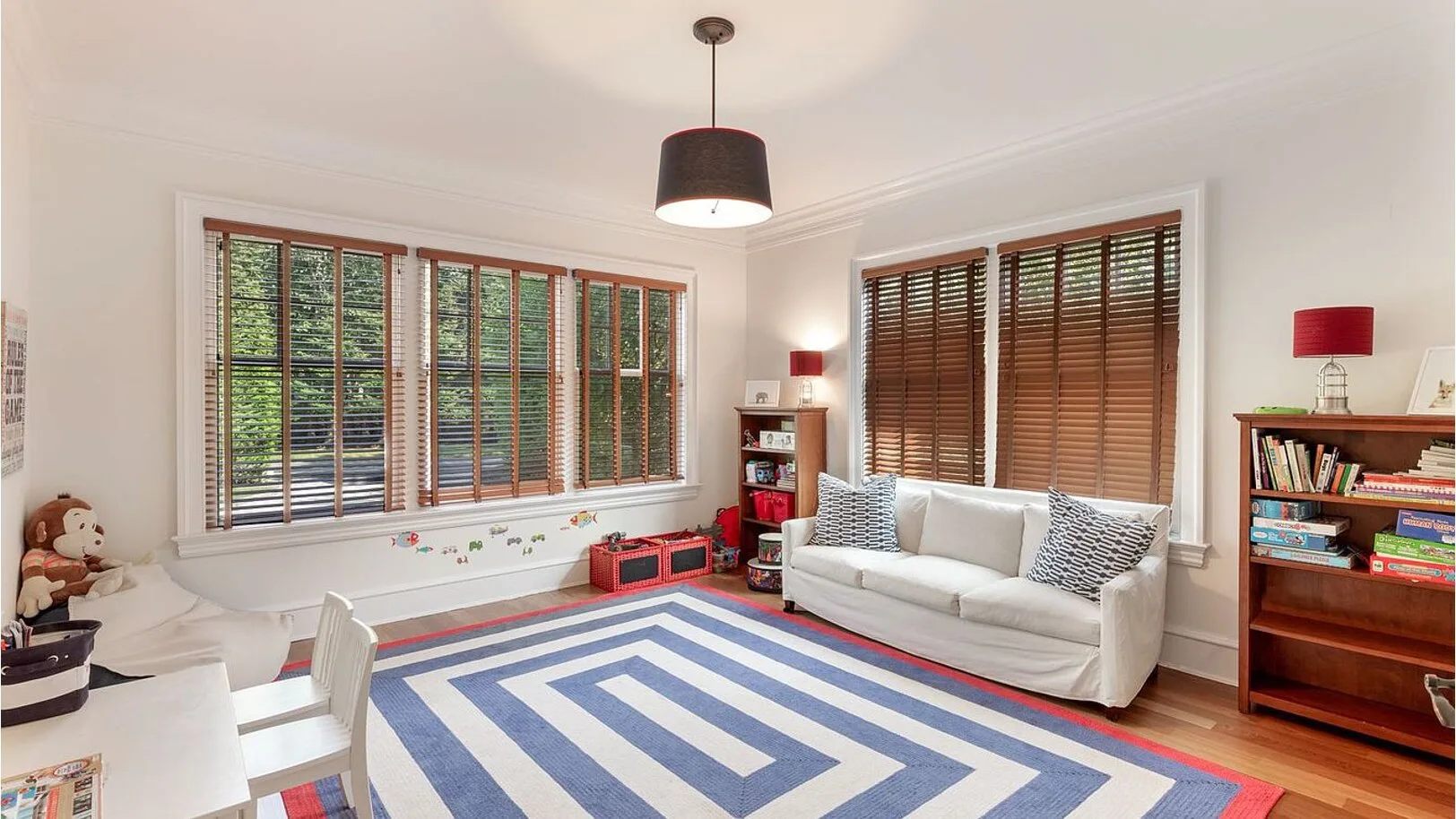 A bright living room with a white sofa and a blue geometric rug.