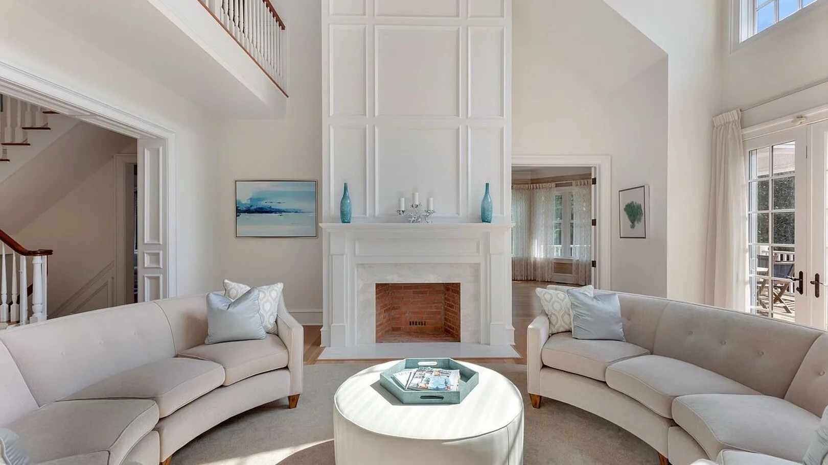 A bright living room with curved seating arranged around a round coffee table.