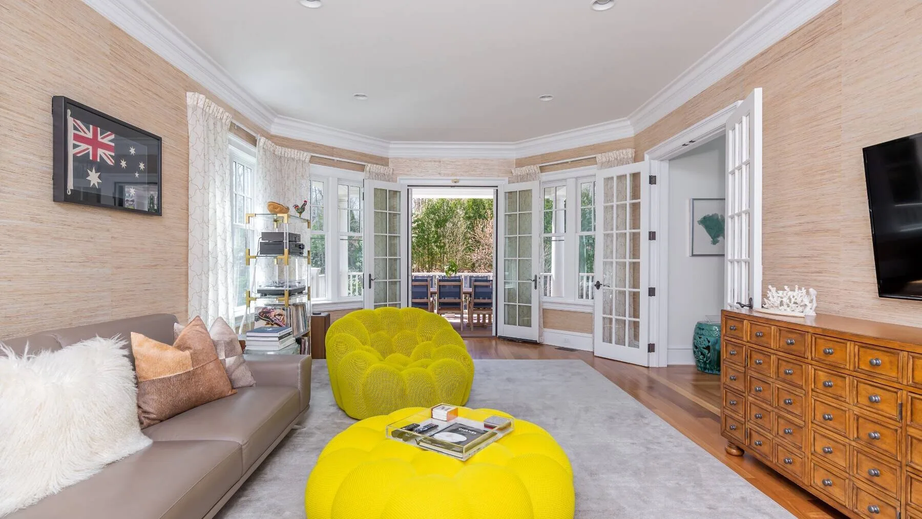 A bright living room with a yellow sofa and a bay window overlooking greenery.