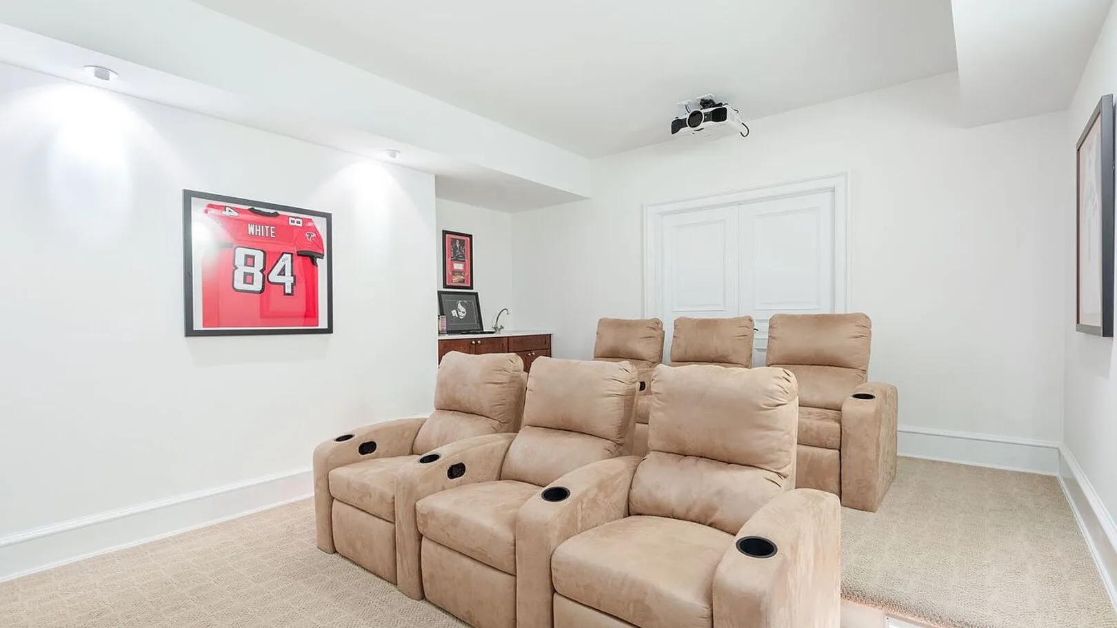 A home theater seating area with a red sports jersey displayed on the wall.