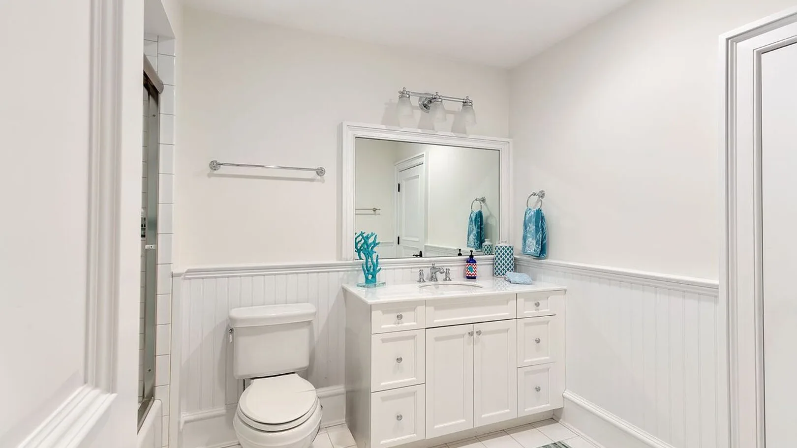 A bright bathroom with a vanity, mirror, and toilet.