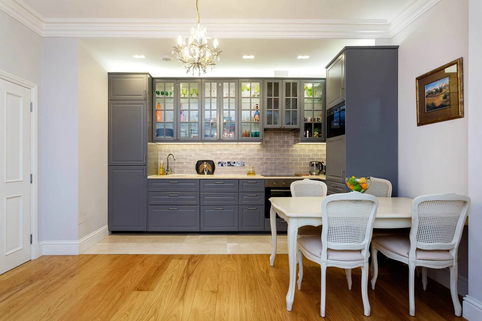 A dining area with a white table and chairs beside a large kitchen.