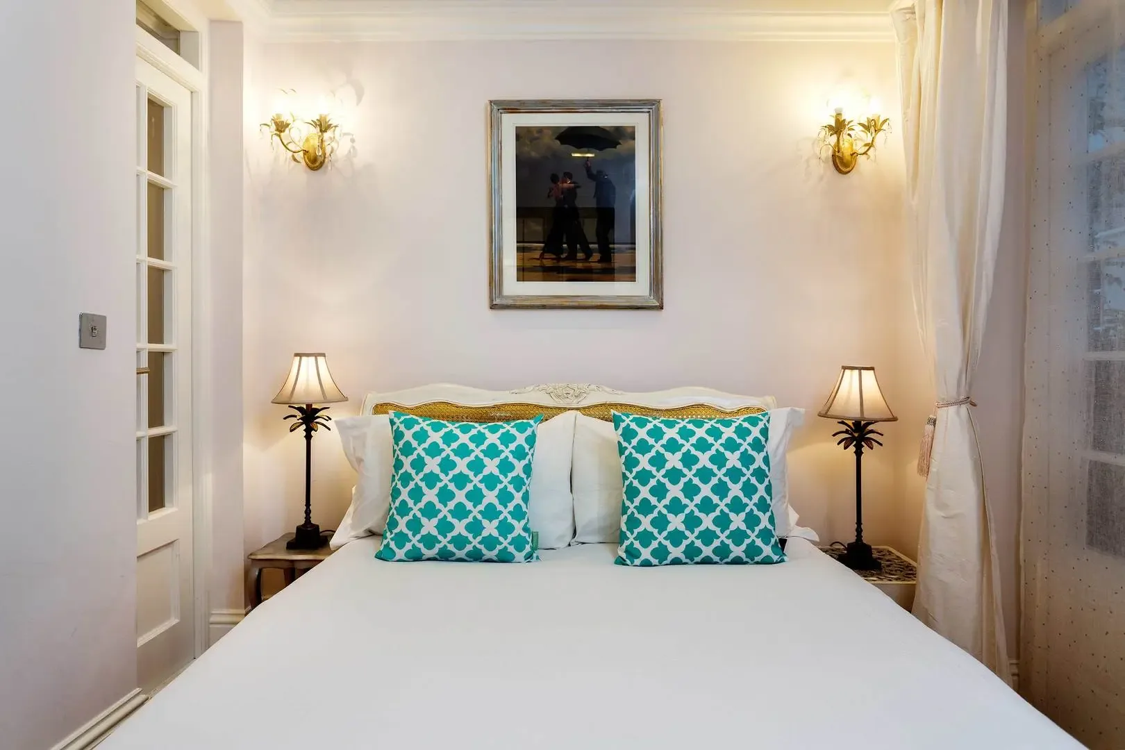 A bedroom with a neatly made bed and matching bedside lamps.