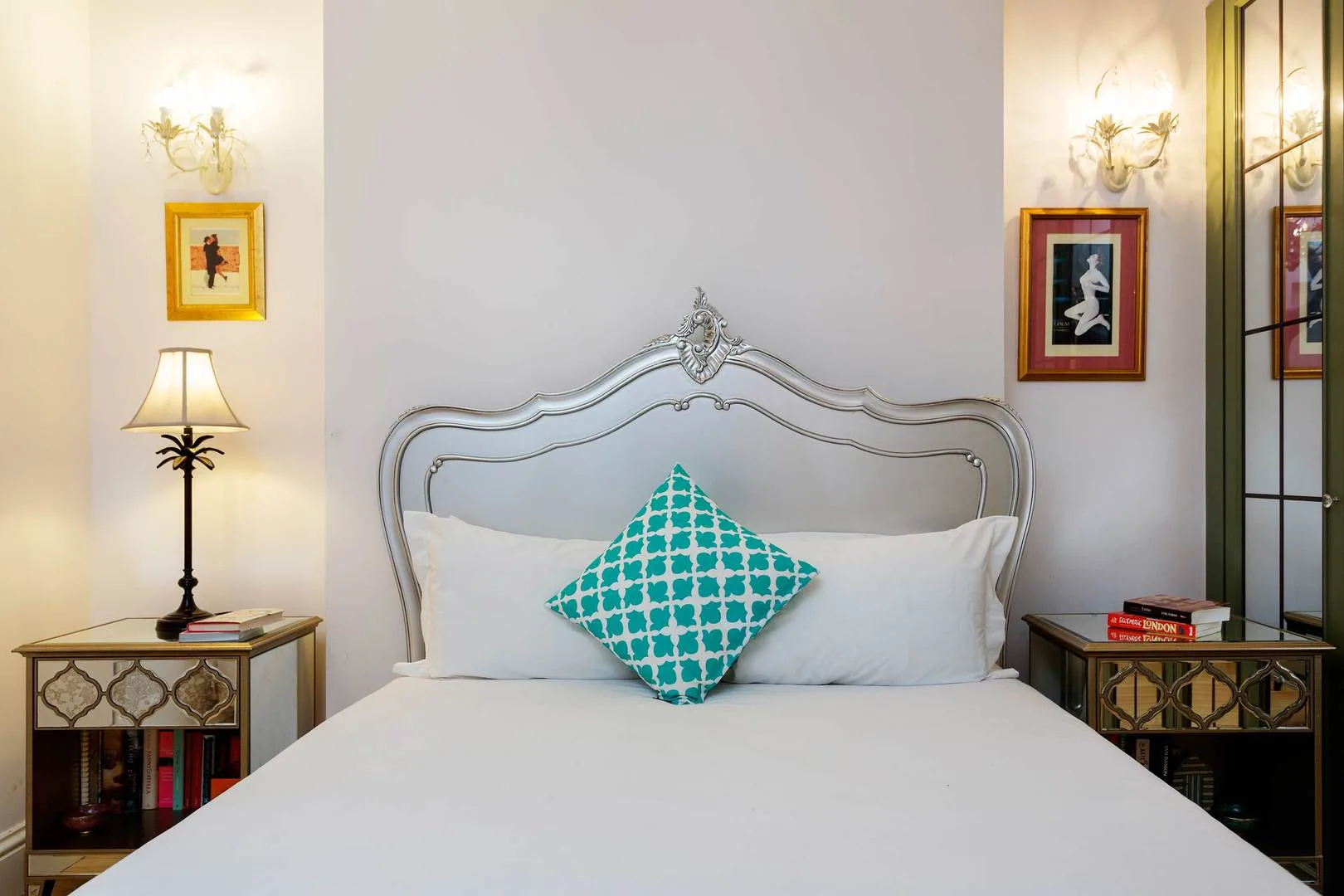 A bedroom with a neatly made bed and a turquoise patterned cushion.