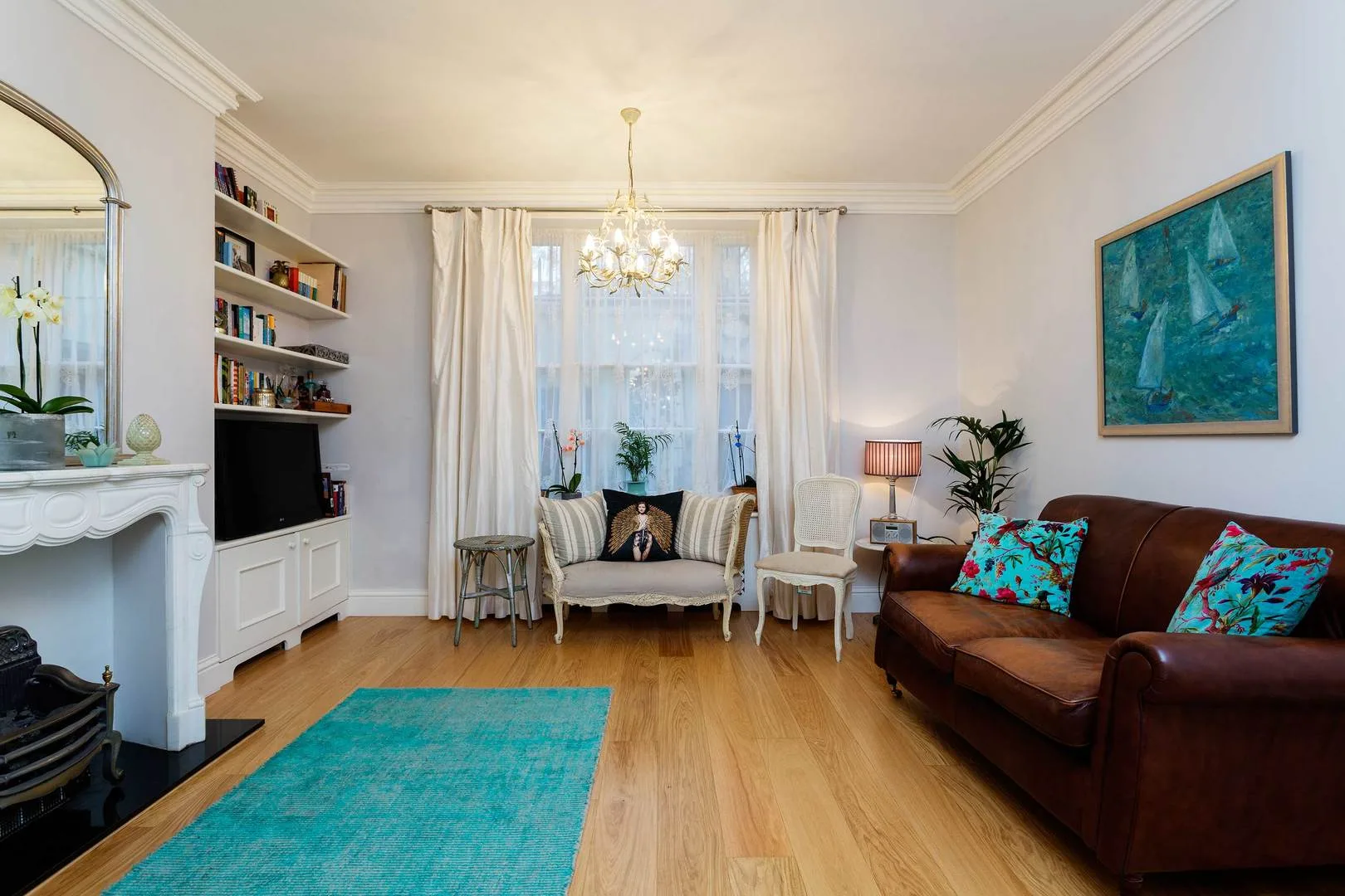 A bright living room with seating, a fireplace, and a turquoise rug.