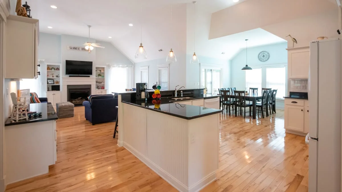 An open kitchen and dining area with a central island and light wood floors.