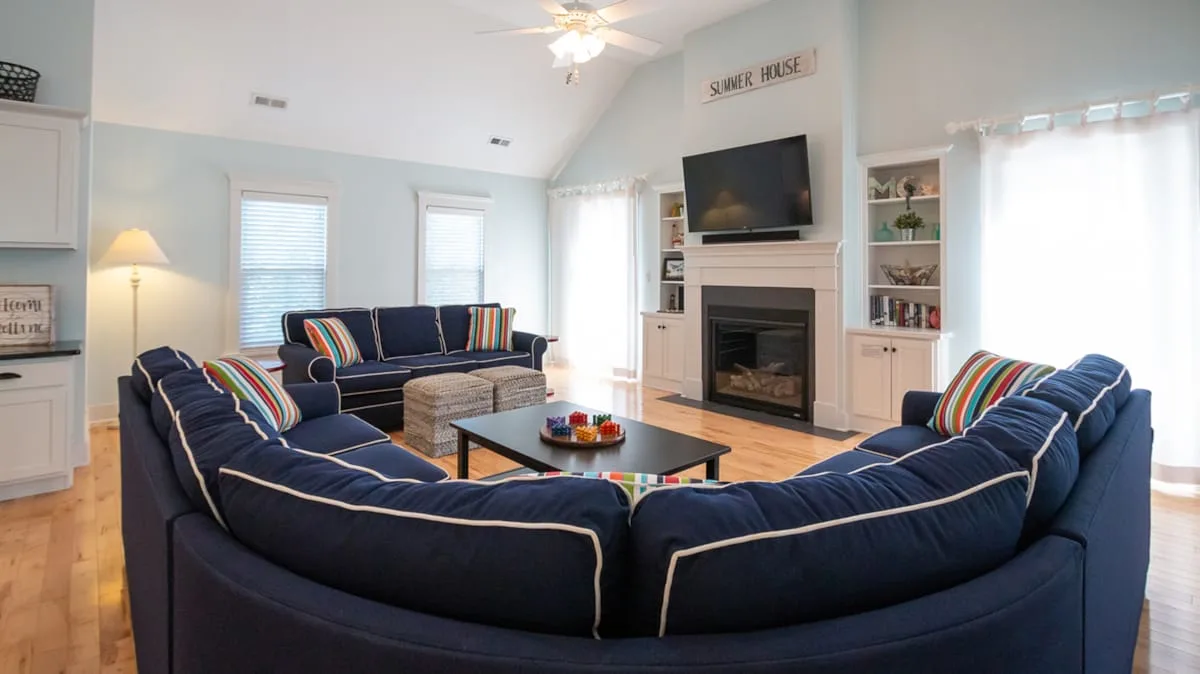 A living room with dark blue seating arranged around a coffee table and fireplace.