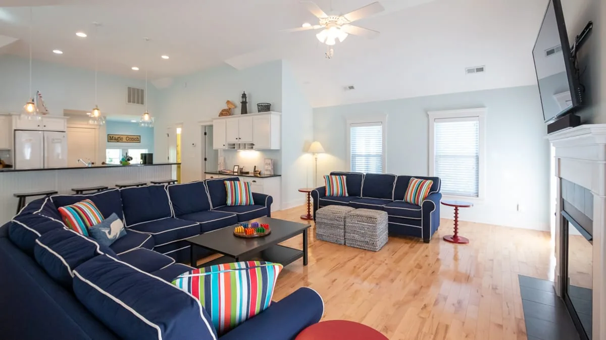 An open living room with dark seating, colorful cushions, and a coffee table.