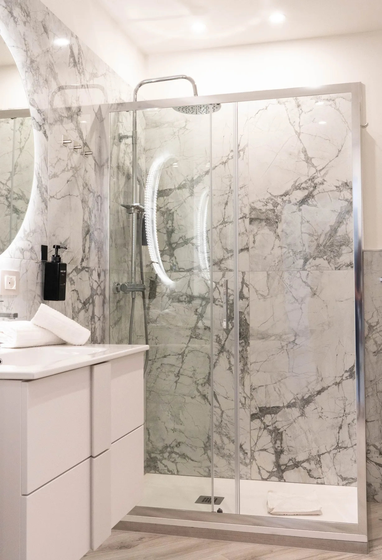 A marble-patterned bathroom with a glass shower and vanity.