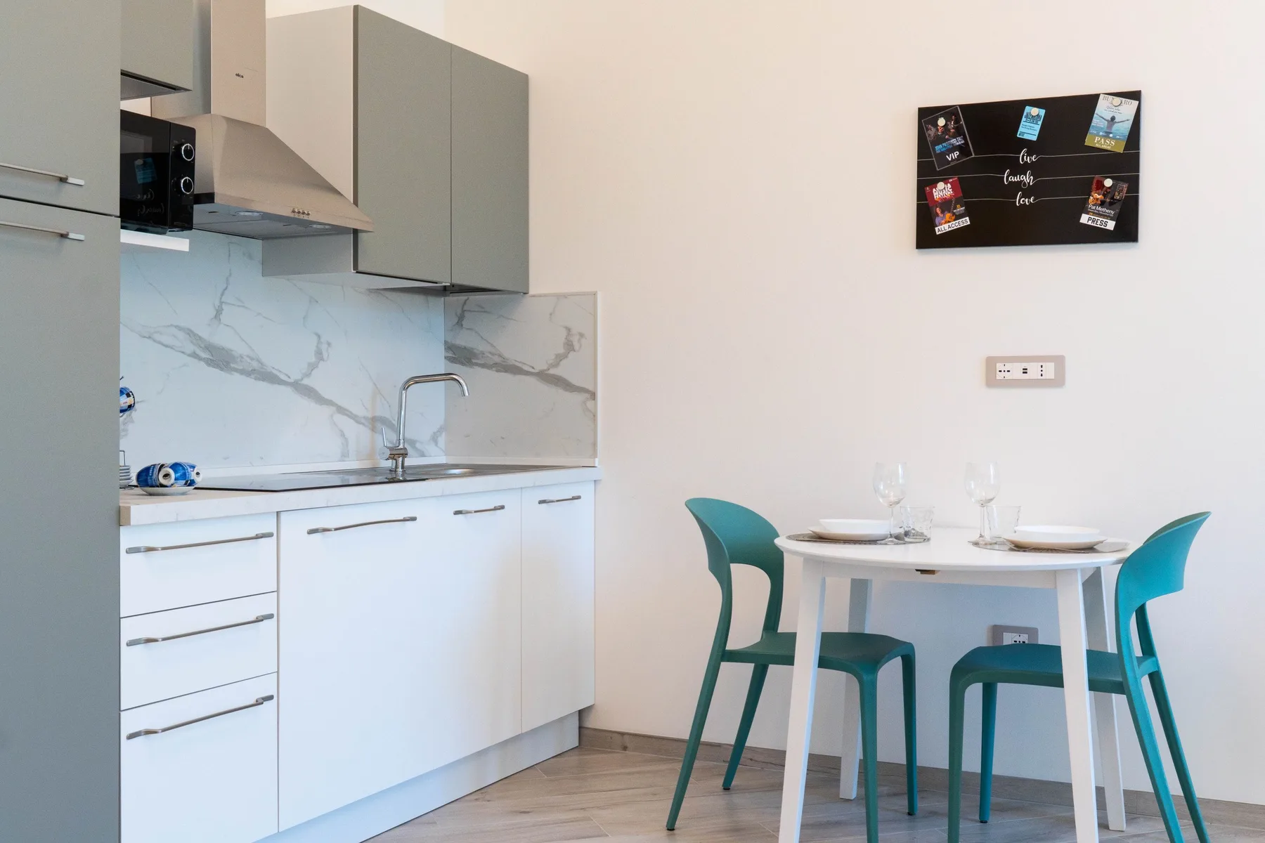A compact kitchen and dining area with a table and turquoise seating.