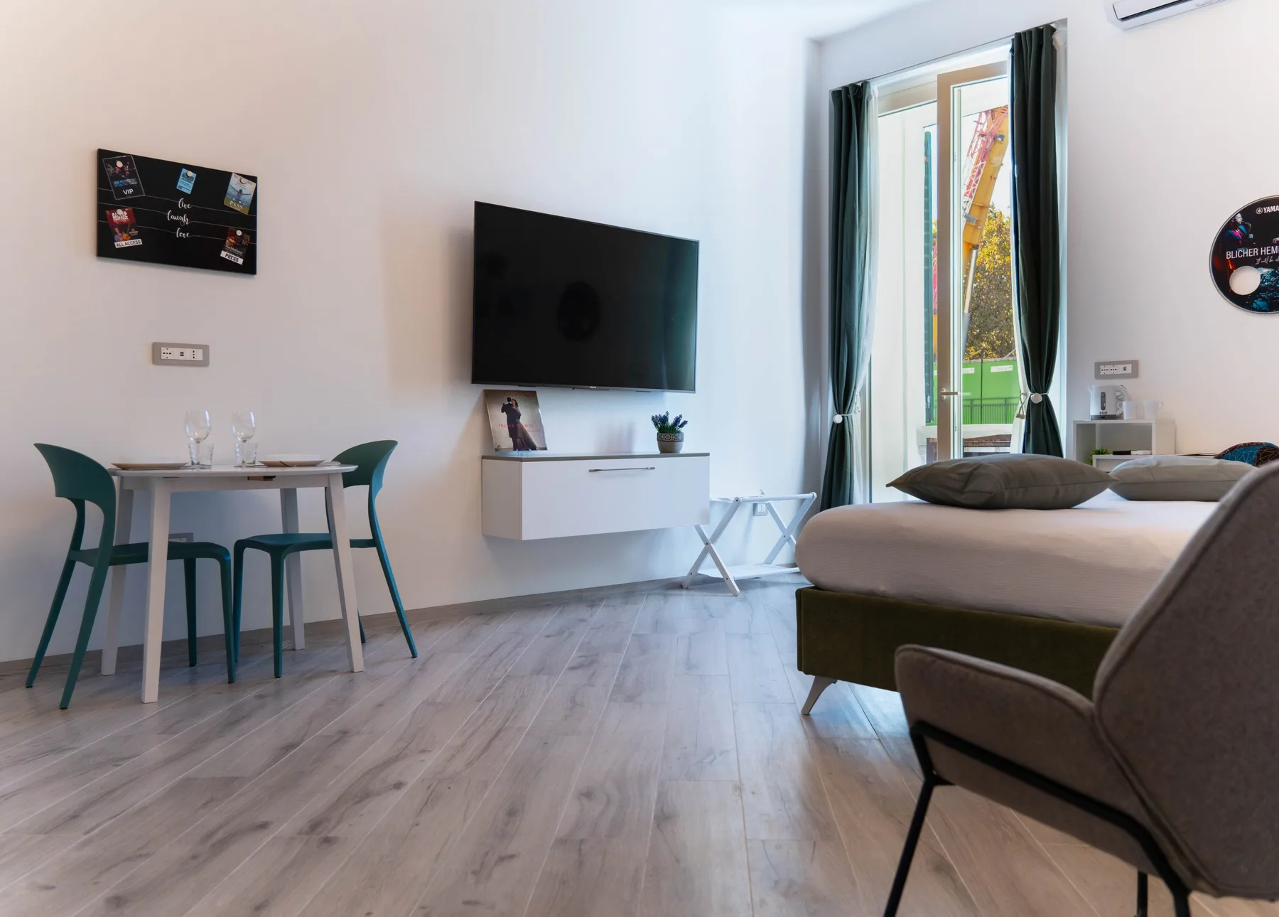 A bright bedroom with a bed, television, and small dining table.