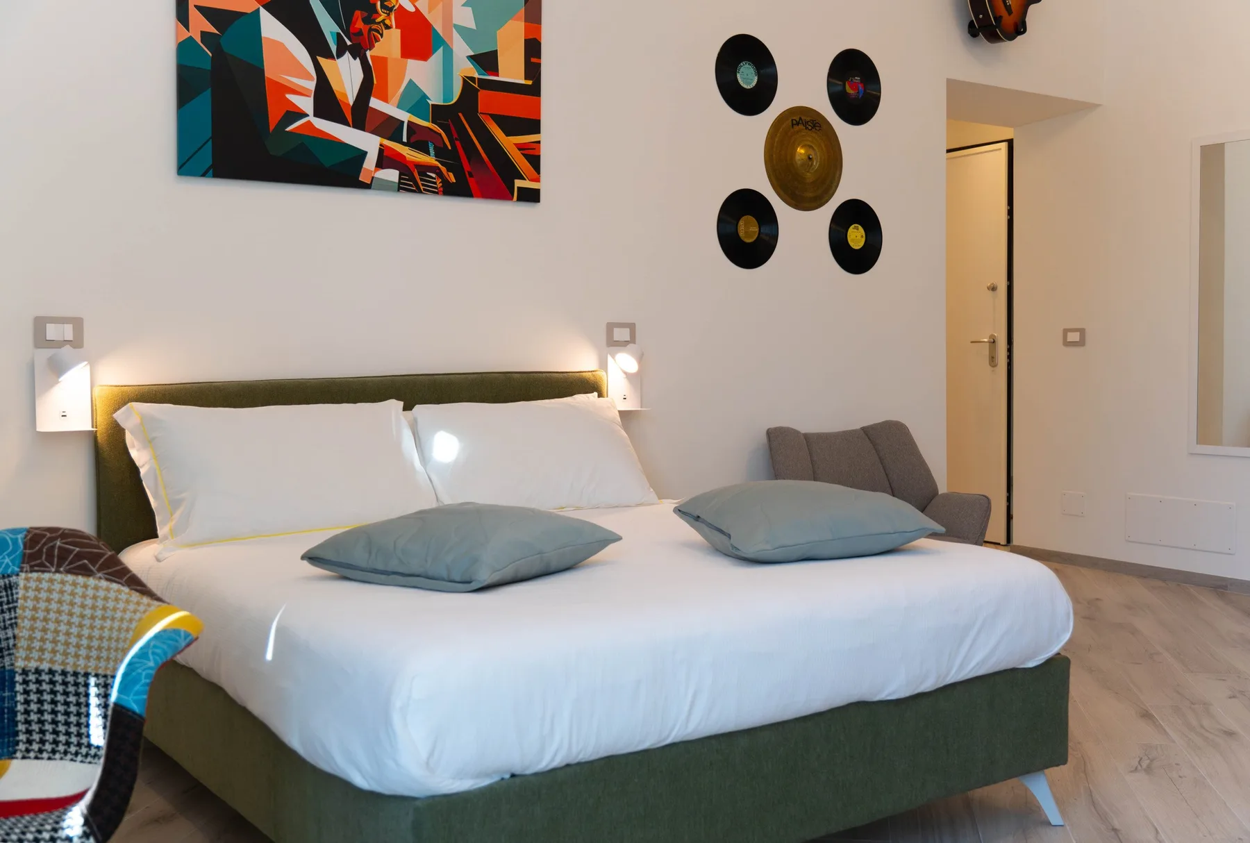 A bedroom with a neatly made bed and colorful artwork on the wall.