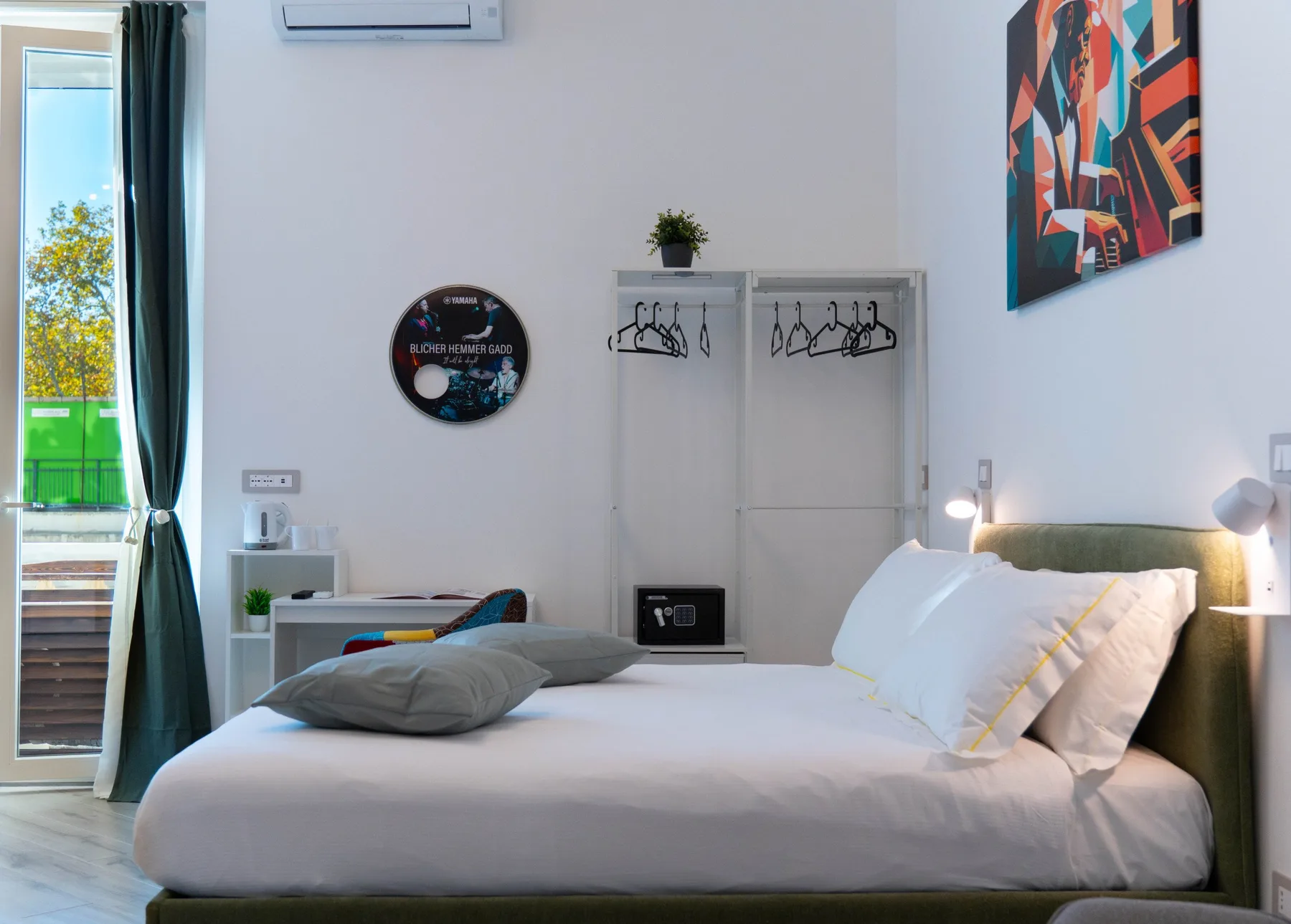 A bedroom with a neatly made bed and colorful artwork on the wall.