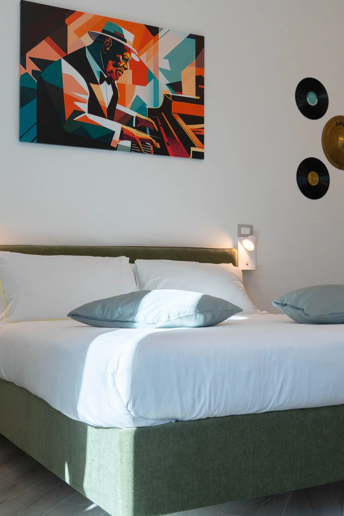 A bedroom with a neatly made bed beneath colorful wall art.