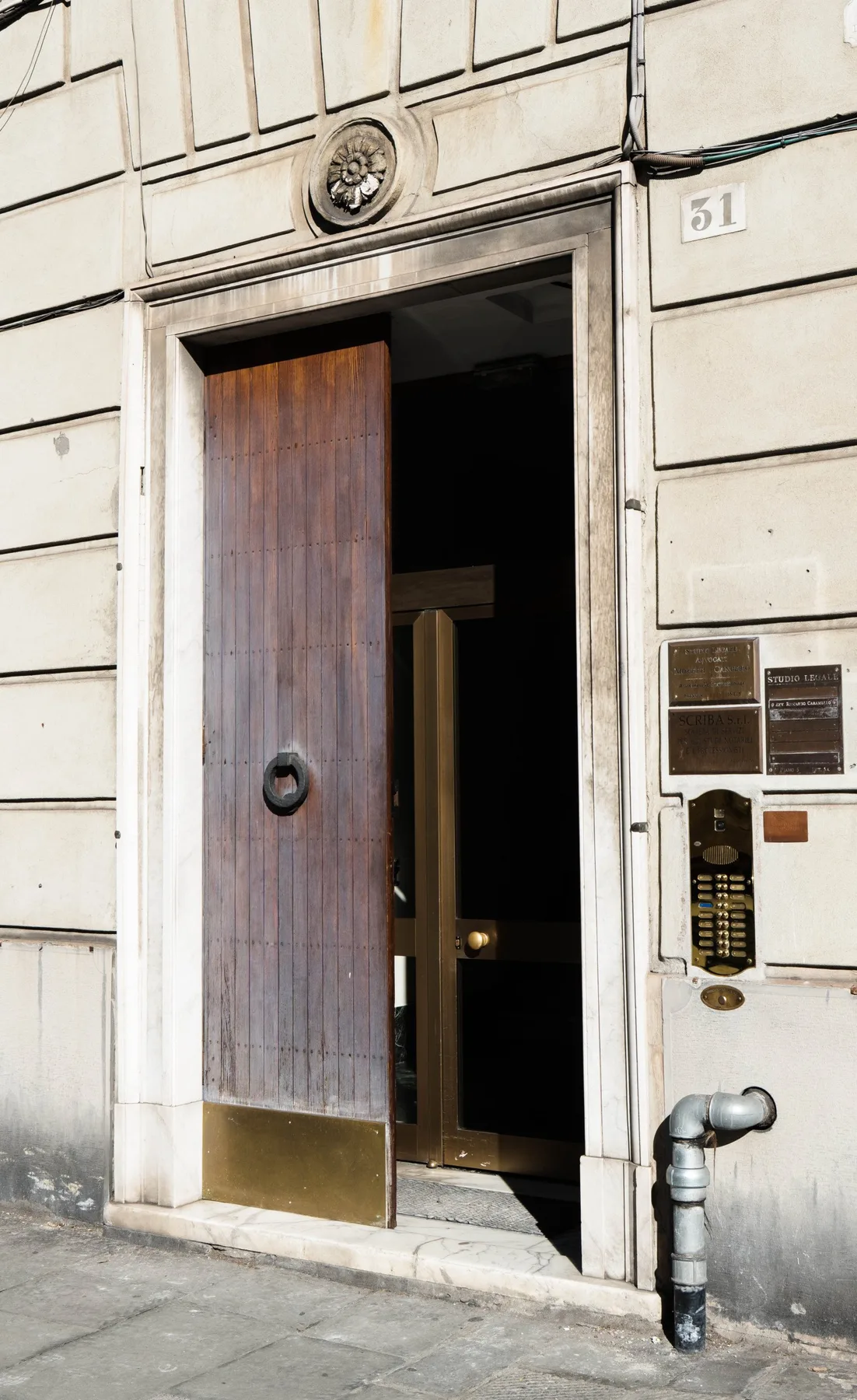 A stone building entrance with a tall wooden door partly open.