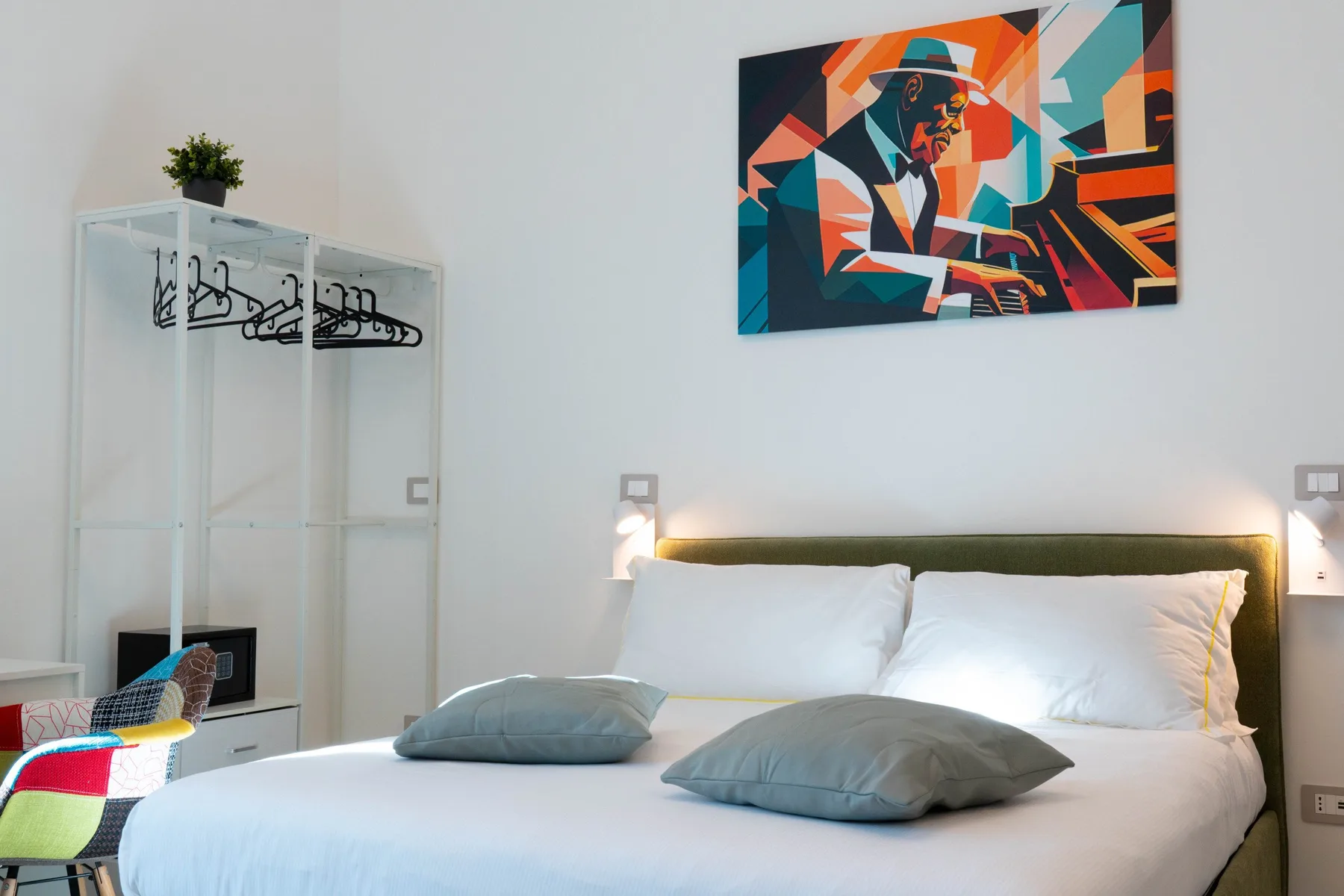A bedroom with a neatly made bed and colorful artwork above the headboard.