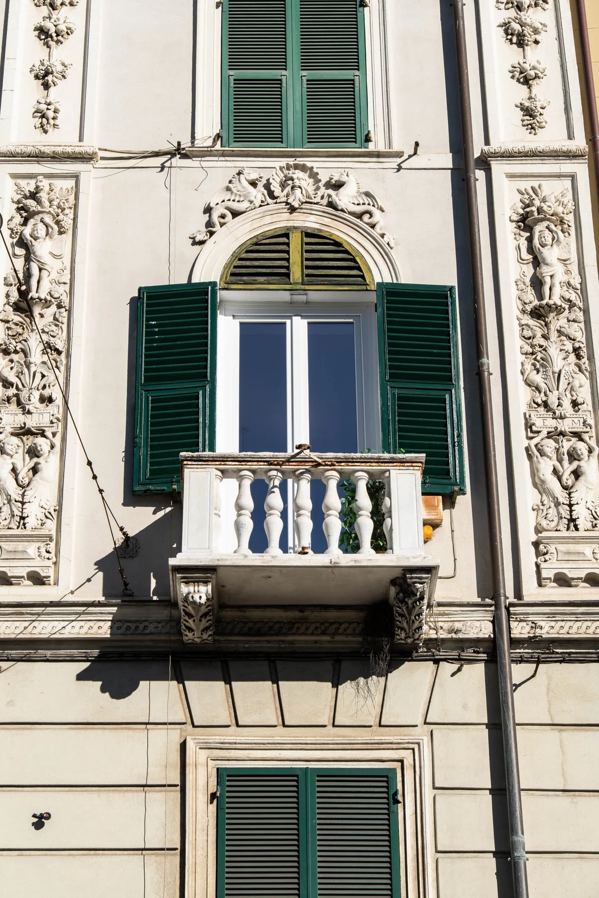 An ornate building facade with green shutters and a small balcony.