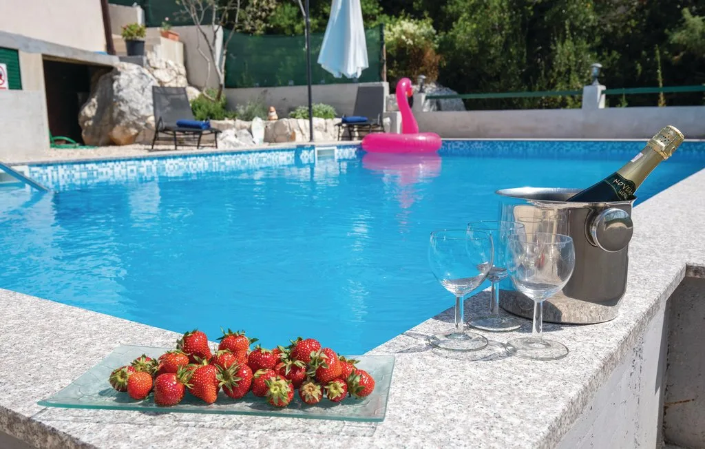 Una piscina con un flotador rosa, copas y fresas en el borde.