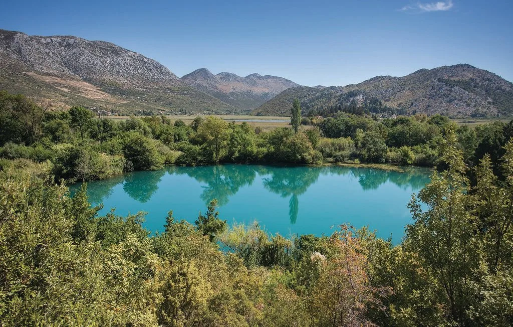 Un lago turquesa está rodeado de vegetación densa y montañas.