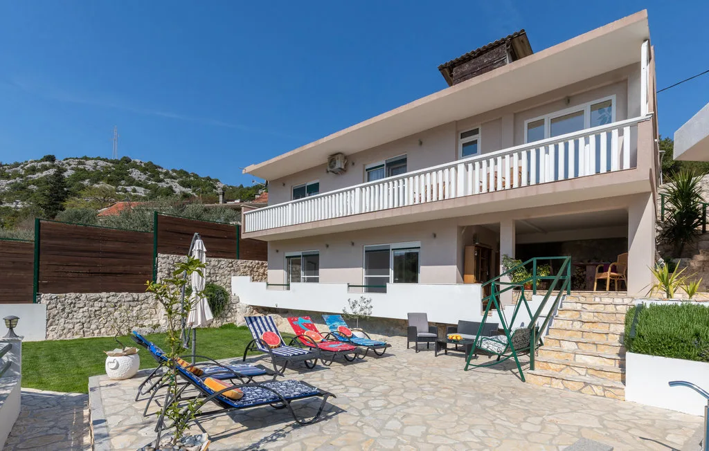 Una casa moderna da a un patio pavimentado con asientos al aire libre.
