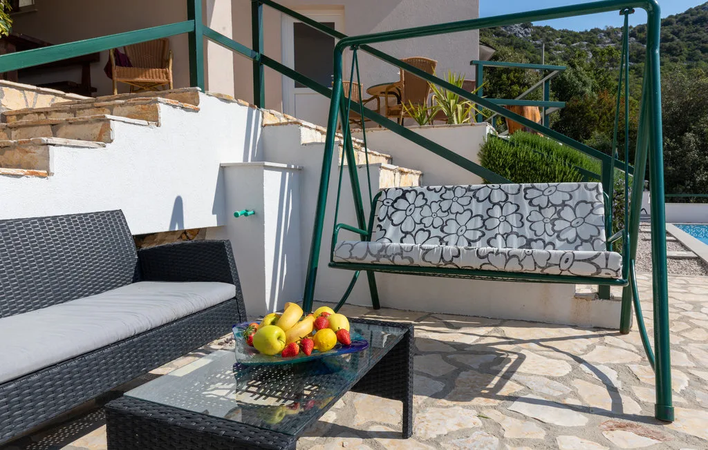 Un patio al aire libre con asientos acolchados, un columpio y un frutero.
