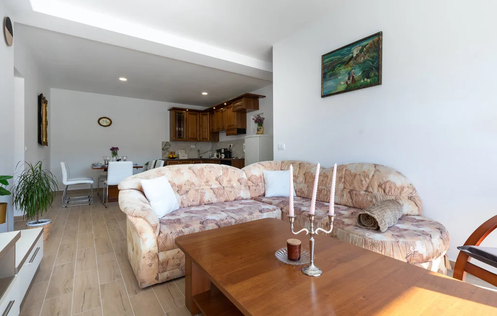 Sala de estar con sofá esquinero y mesa de centro, junto a un comedor y una cocina.