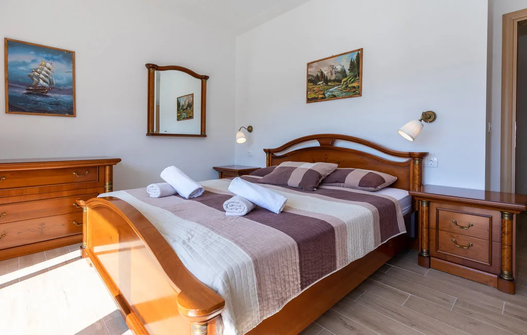 Un dormitorio con una cama de madera, ropa de cama estampada y muebles de madera a juego.
