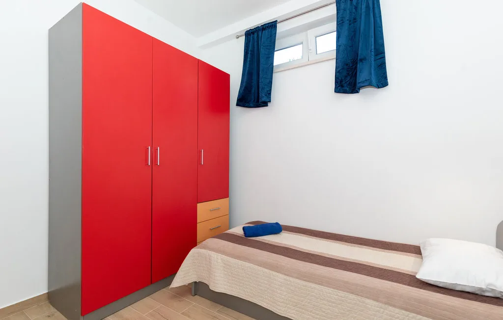 Un dormitorio con un armario rojo y una cama individual.