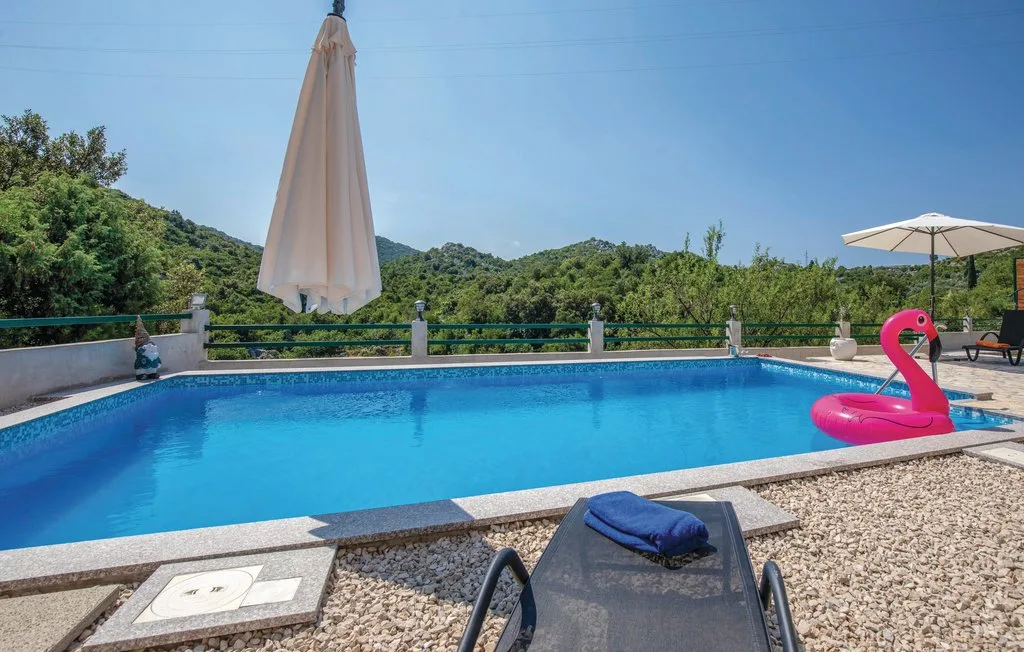 Una piscina al aire libre rodeada de vegetación, con un flotador inflable rosa.